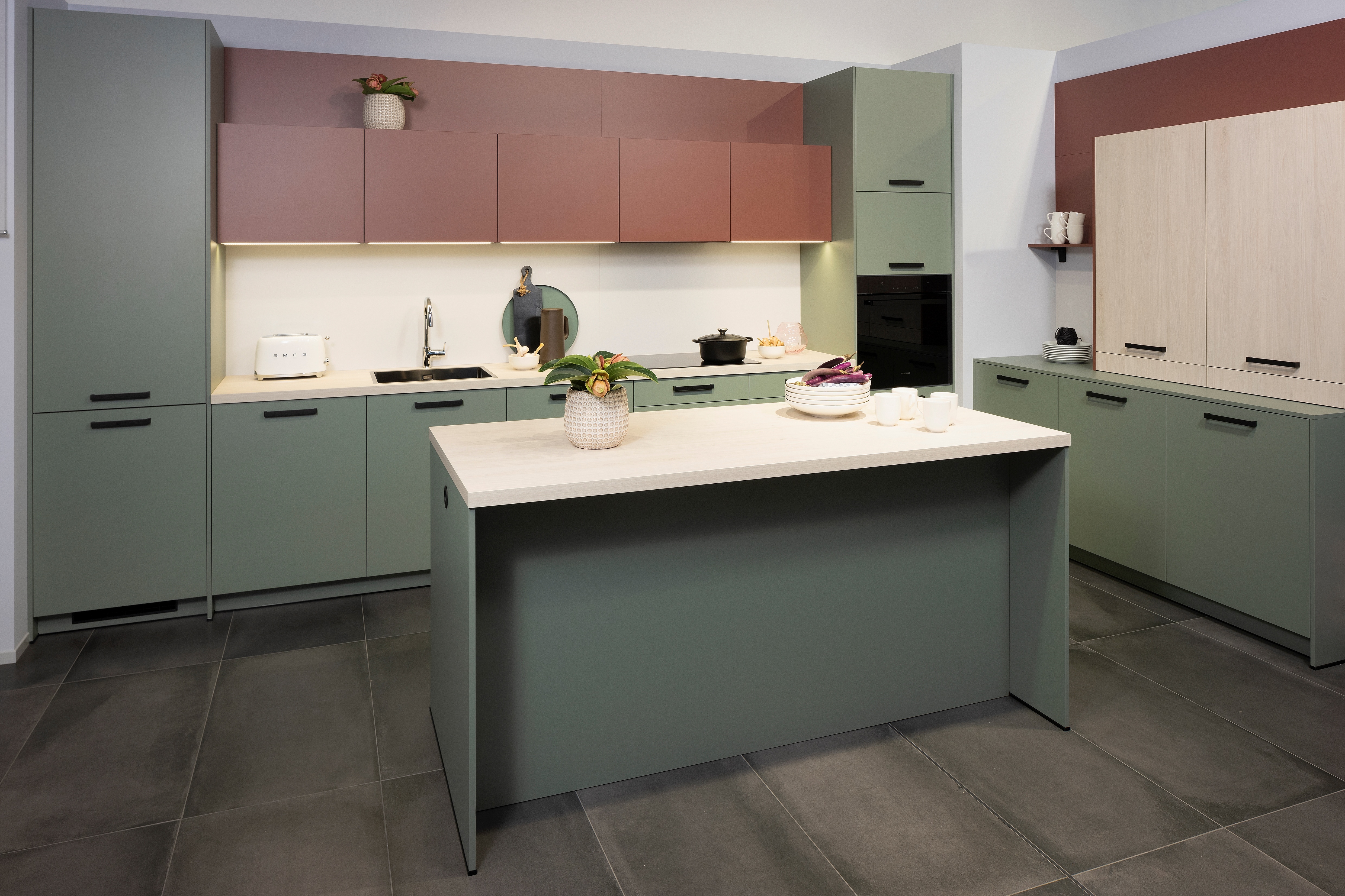 APL: White Oak Front: Pastell Eukalyptus Front: Pastell Oxidrot Korpus: Seidengrau Griff: Bügelgriff Geräte: Daewoo Armatur: Ukinox Spüle: Ukinox  Features: neue Fronten in Pastell kombiniert, neuer Haubenschrank für Dunstabzug, Handtuchhalter-Auszug, eingekofferte Wandschränke mit Klappe.