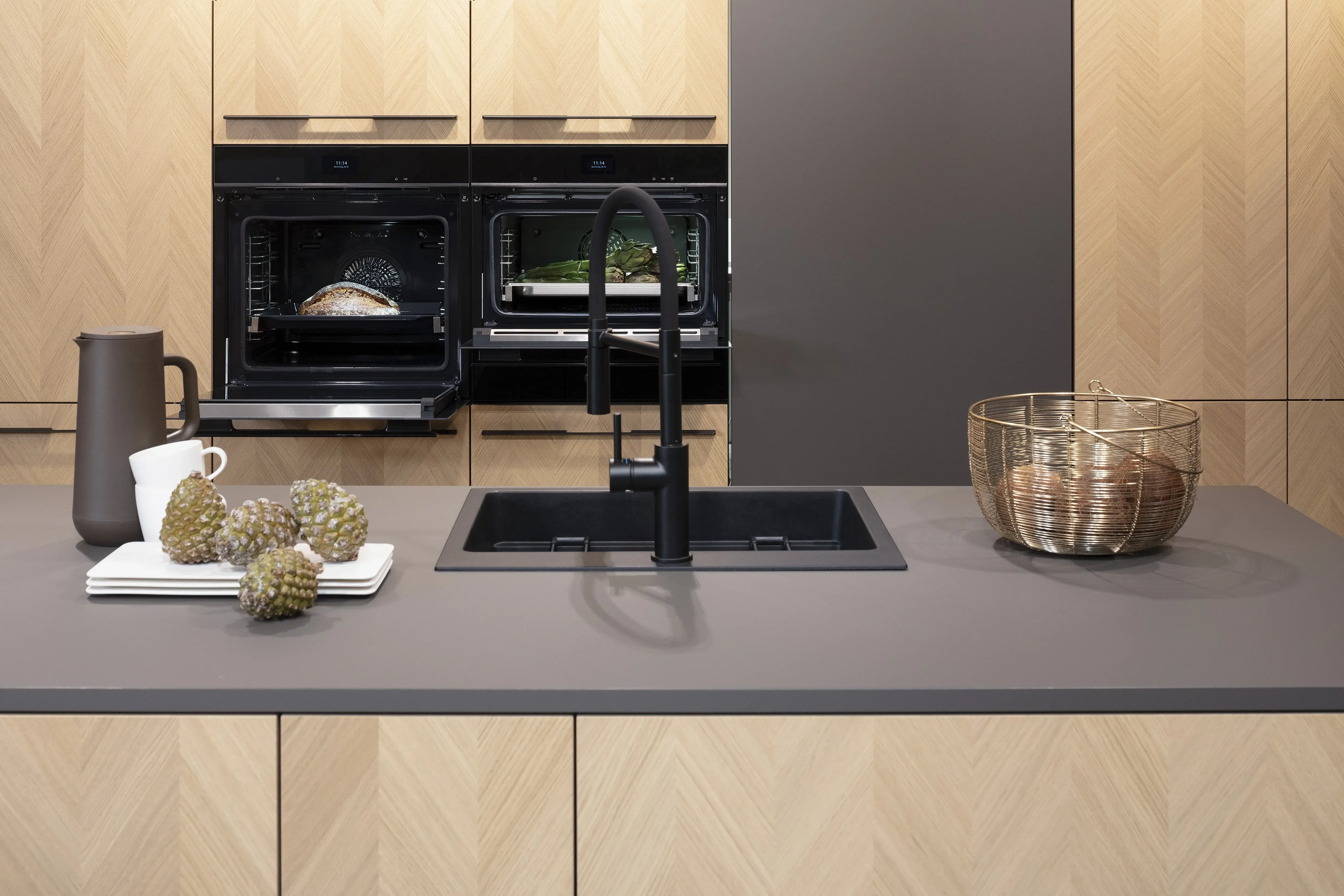 Front: Intarsia Gavi Eiche Furnier Resopal Brown Powder supermatt Korpus Schwarz APL: Resopal Brown Powder supermatt Geräte: Siemens Studio Line Spüle und Armatur: Blanco   Features: Front Echtholz Fischgrät-Optik, Kombination Echtholz und Resopal supermatt, Einbautür in Frontmaterial Resopal, Küchentheke Massivholz, APL = Korpusfarbe = Frontmaterial, Kombination Griffleiste und grifflos, Korpus in Frontmaterial, Wärmeschublade, Spüle und Armatur Schwarz, Besteckeinsatz. 